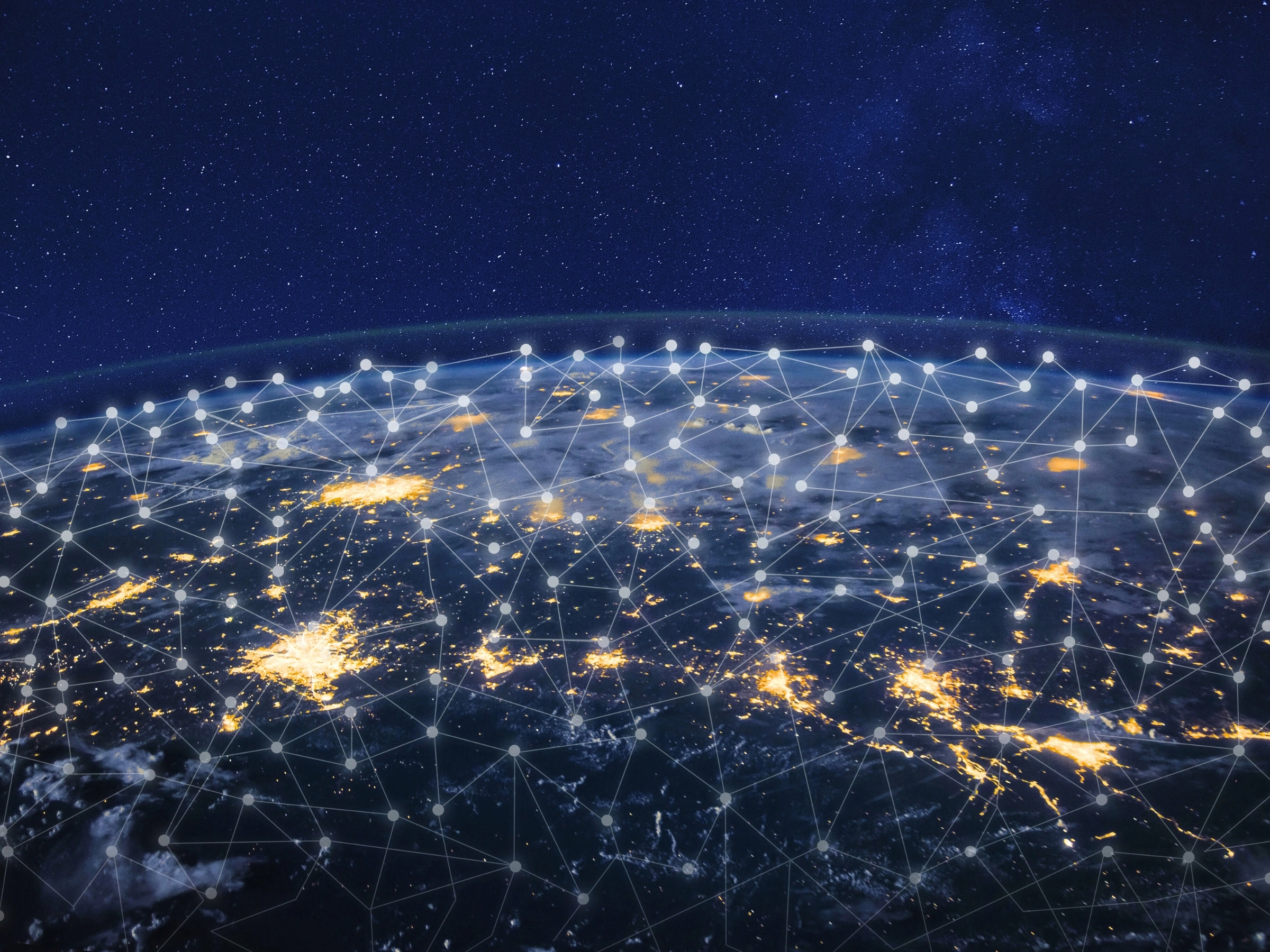 Satellite view of Earth at night showing illuminated cities connected by a digital network of glowing lines and nodes, symbolizing global communication and connectivity.